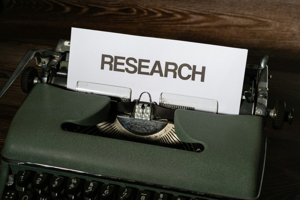 A green typewriter. The word research has bee typed on to it.